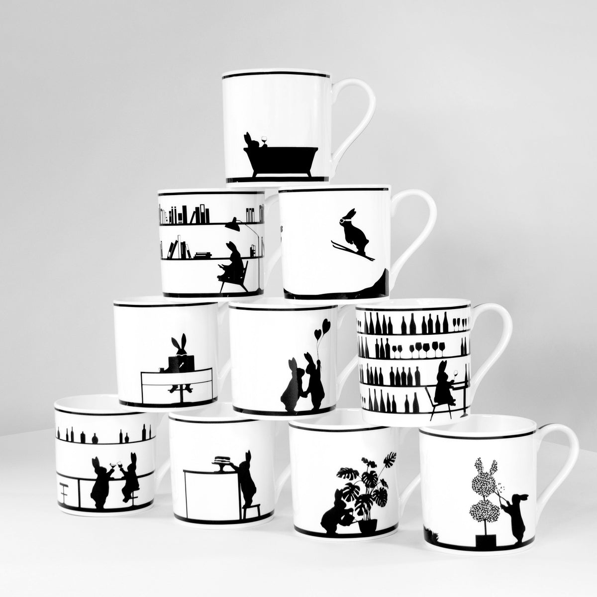 A set of white ceramic mugs with various black-and-white comic strip designs, including characters and scenarios such as a rabbit.